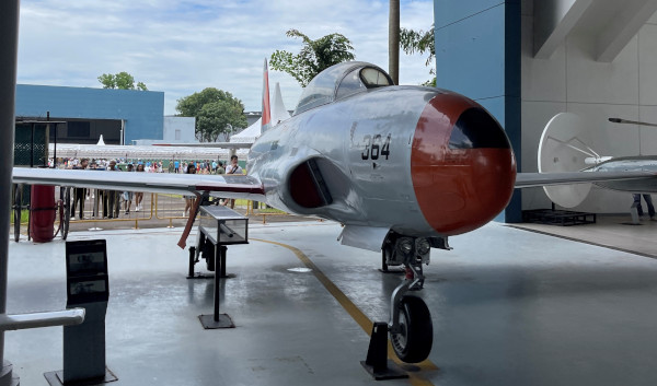 Vintage silver and orange jet aircraft with the number 364 displayed outdoors.